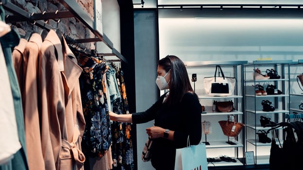A shopper looks through racks of clothing inside a boutique fashion store.