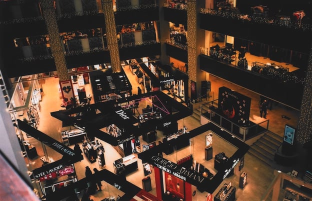 A bird's eye view of a multiple-story interior mall filled with luxury brand kiosks