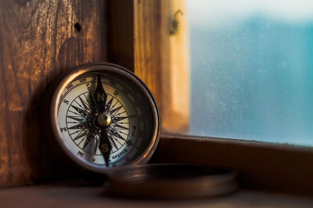 An antique compass rests near a window, longing for a return to the sea.