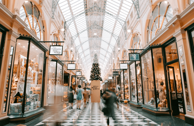 Customers walk through an upscale mall corridor with beautifully decorated storefronts.