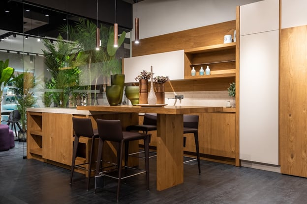An inviting, contemporary kitchen showroom complete with wooden cabinetry, display pieces, and house plants.
